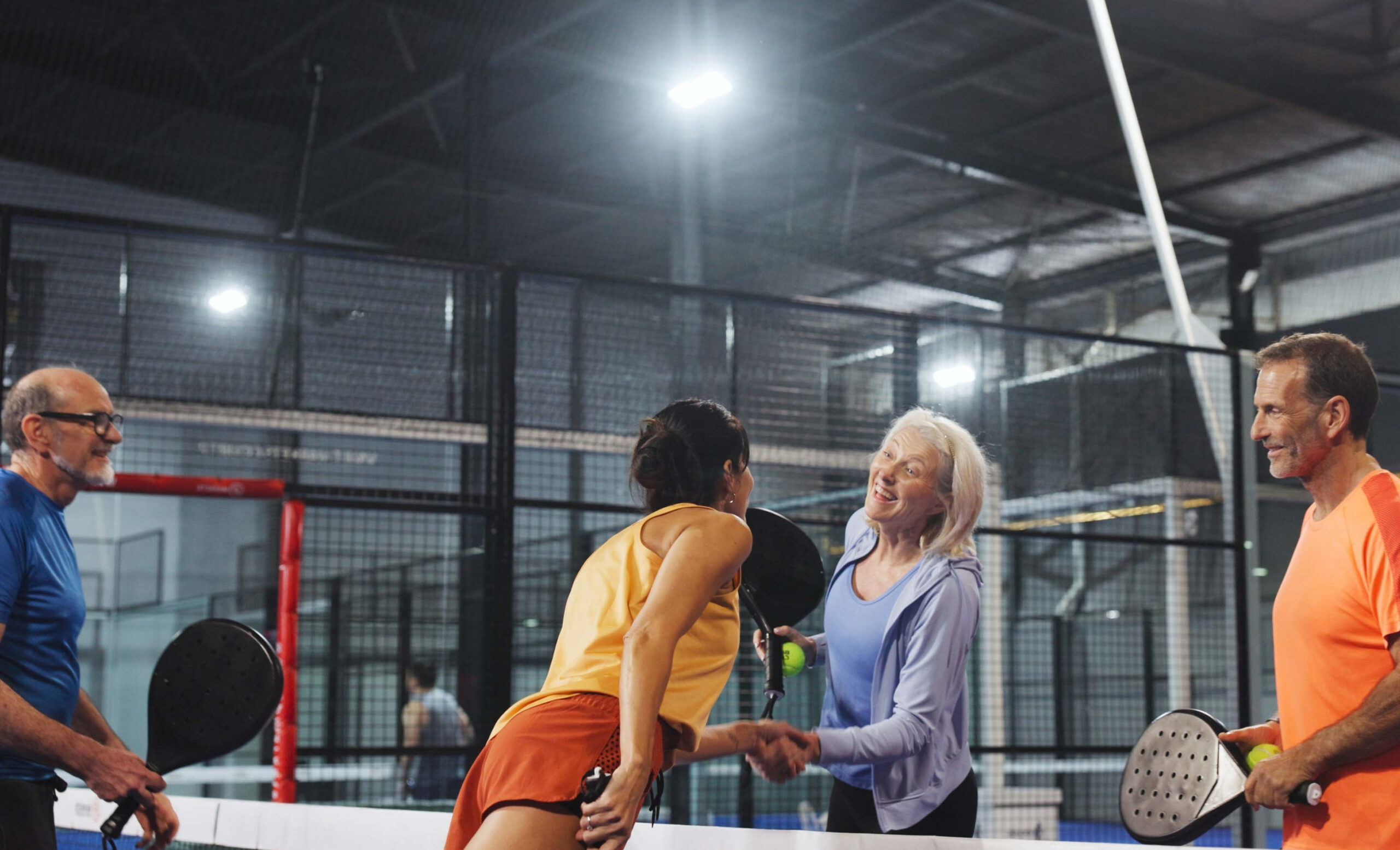 Quatre joueurs se serrant la main après un match de padel indoor